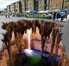 an image of a hole in the ground with water coming out of it and people walking around