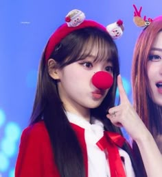 two girls with red noses and clown nose rings posing for the camera, one pointing at her face