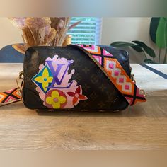 a black purse sitting on top of a wooden table next to a vase filled with flowers