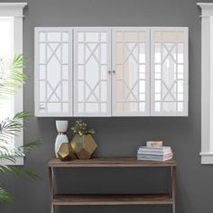 a white cabinet sitting on top of a wooden shelf next to a potted plant