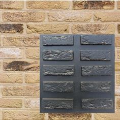 a metal plaque mounted to the side of a brick wall with several different types of tiles on it