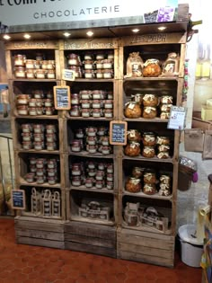 a display case filled with lots of different types of food on wooden shelves next to a tiled floor