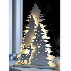 a lighted christmas tree in front of a window with the light on it's side