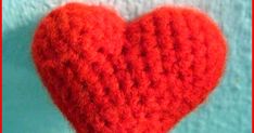 a red crocheted heart hanging from a hook on a blue and white wall