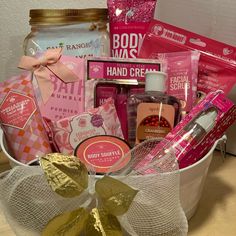 a white basket filled with lots of pink and gold items sitting on top of a wooden table