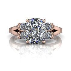 three stone engagement ring with diamonds on the sides and an oval shaped diamond in the center