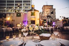 the table is set for an event with white and pink flowers in centerpieces