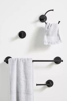 two towels hanging on the wall next to towel racks and black brackets with white towels