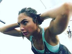 a woman holding her head with one hand while standing in front of a gym floor