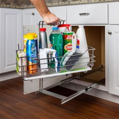 a person is holding the bottom rack of a dishwasher in a kitchen with white cabinets and wood flooring