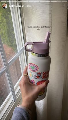 a person holding a water bottle in front of a window with the words hello kitty on it