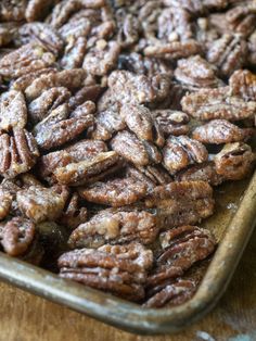 a tray full of pecans sitting on top of a wooden table next to a knife