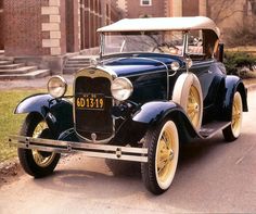 an old car is parked on the side of the road in front of a building