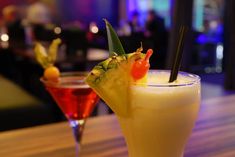 two cocktails sitting on top of a wooden table