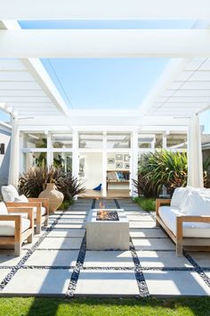 an outdoor living area with couches, tables and fire pit in the middle of it