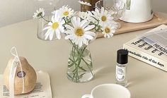 a vase with daisies in it sitting on a table next to some books and other items