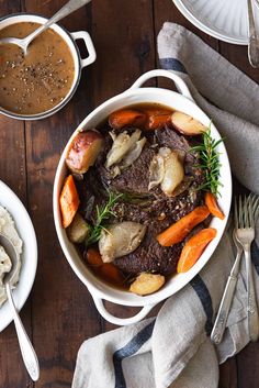 a bowl of beef stew with carrots, potatoes and gravy on a wooden table