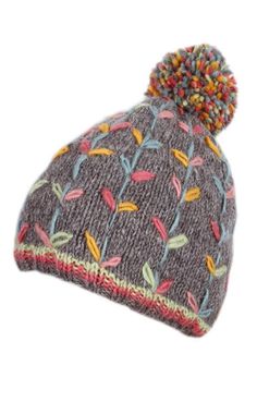 a knitted beanie with colorful flowers on the front and sides, one pom - pom at the top