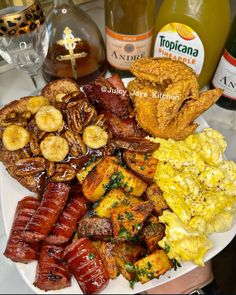 a plate with sausages, eggs, and other foods on it next to two bottles of booze