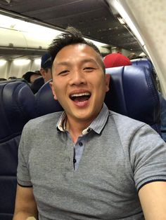 a man sitting on an airplane with his eyes closed and mouth wide open, laughing