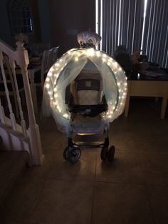 a baby stroller with fairy lights on it's canopy in the middle of a room