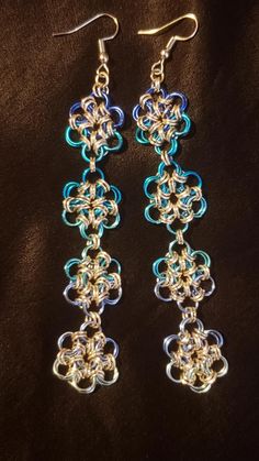 two pairs of earrings with blue and silver chainmails on black fabric, one is dangling