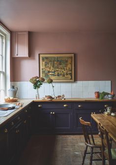 a kitchen with purple painted walls and wooden furniture, along with a painting on the wall