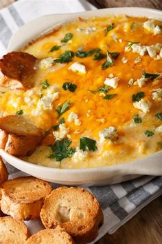 a white bowl filled with cheesy dip next to crackers on a checkered napkin