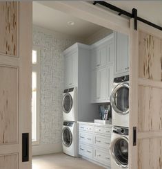 a washer and dryer are in the middle of a room with white cabinets