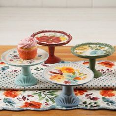 several plates with cupcakes on them sitting on a table