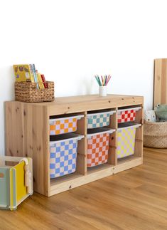 a wooden shelf with baskets on top of it next to a stuffed animal and other toys