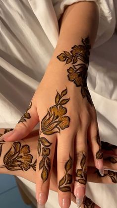 a woman's hands with hennap and flowers painted on her hand,