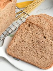 two slices of bread sitting on top of a white plate next to a basket with bananas