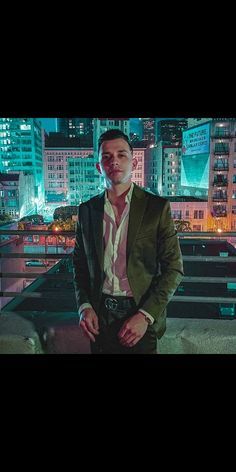 a man wearing a suit and tie standing in front of a cityscape at night