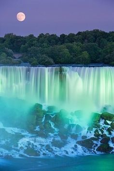 the niagara falls at night with full moon in the sky and water flowing over them