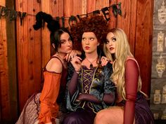 three women dressed in costumes sitting next to each other and posing for the camera with their hands on their hips