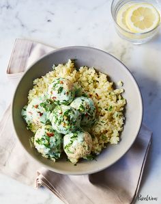 a bowl filled with rice and meat next to a glass of lemonade on a table