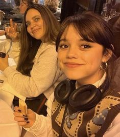 two women sitting next to each other at a table with food in front of them