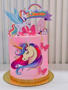 a pink cake decorated with unicorns and butterflies