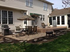 a patio with chairs and an umbrella in front of a house