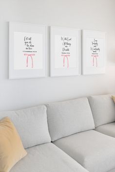 three framed pictures hang on the wall above a couch in a white living room with beige pillows