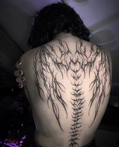 the back of a woman's body with an intricate tattoo design on her shoulder