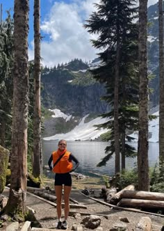 a woman in an orange vest is standing by some trees