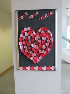 a sign that says love your library with hearts cut out of paper on the front