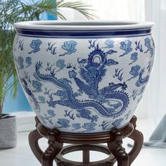 a blue and white vase sitting on top of a wooden stand next to a potted plant