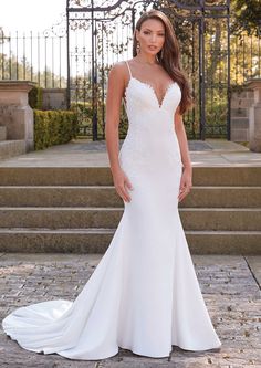 a woman in a white wedding dress posing for the camera with her hands on her hips