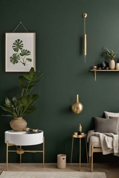 a living room with green walls, gold accents and plants on the shelf above it