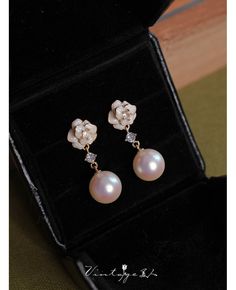 a pair of pearl and diamond earrings in a velvet box with its lid open to show the earring