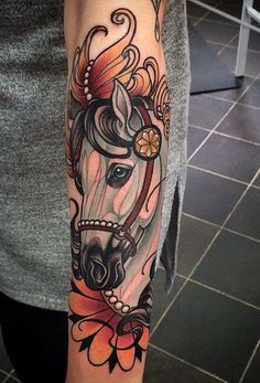 a woman's arm with a horse and flower tattoo design on the left forearm