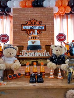 two teddy bears sitting at a table with orange and black balloons in the shape of harley davidson